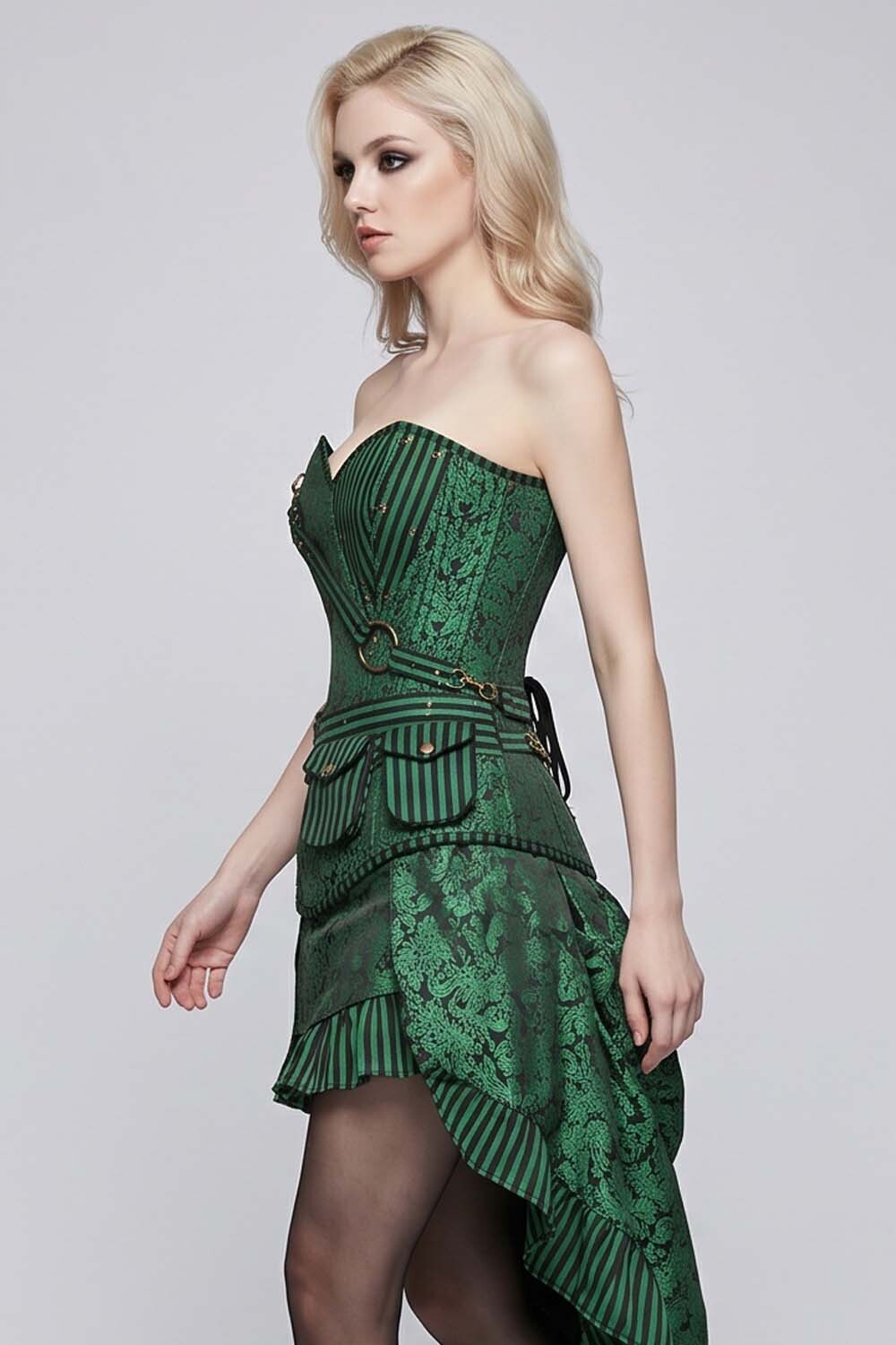 A blonde model wearing a dark green LUXE NOIR CORSET strapless corset-style dress with lace and striped fabric details, paired with sheer black tights, against a light gray studio background.