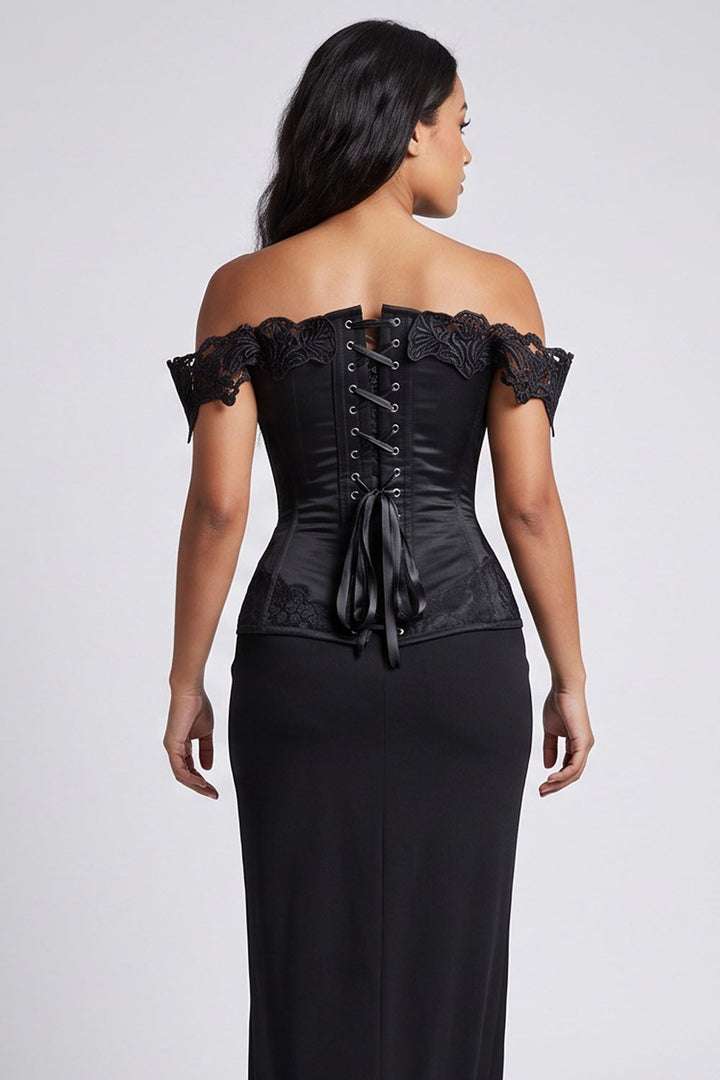 A woman shown from the back wearing a Luxe Noir black off-the-shoulder corset top with lace trim and a long black skirt against a light gray studio background.