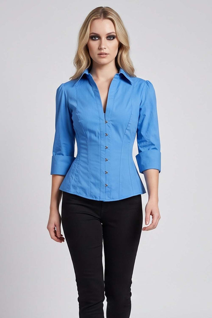 A woman modeling a Luxe Noir  bright blue structured button-front blouse with three-quarter sleeves and black pants, standing against a light gray studio background.