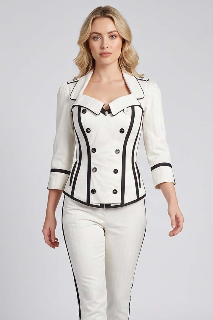 A woman modeling a Luxe Noir  white tailored jacket and matching white pants with black piping and black side stripes, photographed against a light gray studio background.