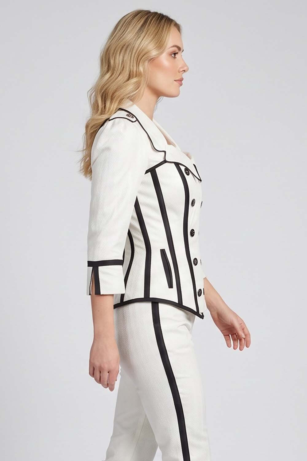 A woman shown in side profile wearing a Luxe Noir white tailored jacket and matching trousers with bold black piping and trim details, photographed against a light gray studio background.