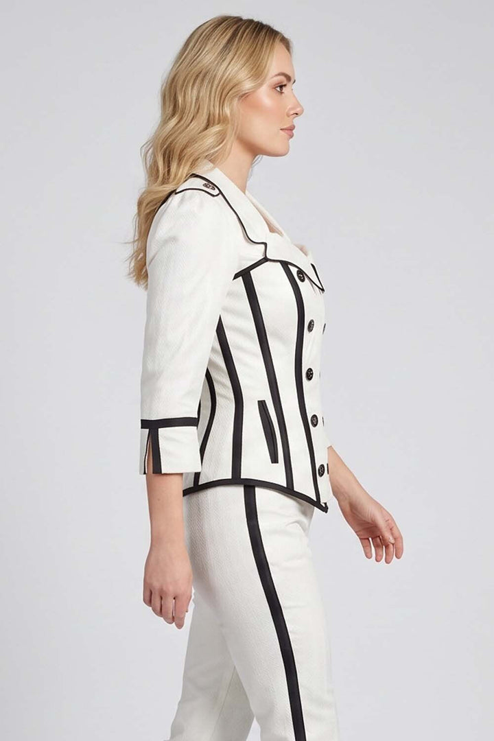 A woman shown in side profile wearing a Luxe Noir white tailored jacket and matching trousers with bold black piping and trim details, photographed against a light gray studio background.