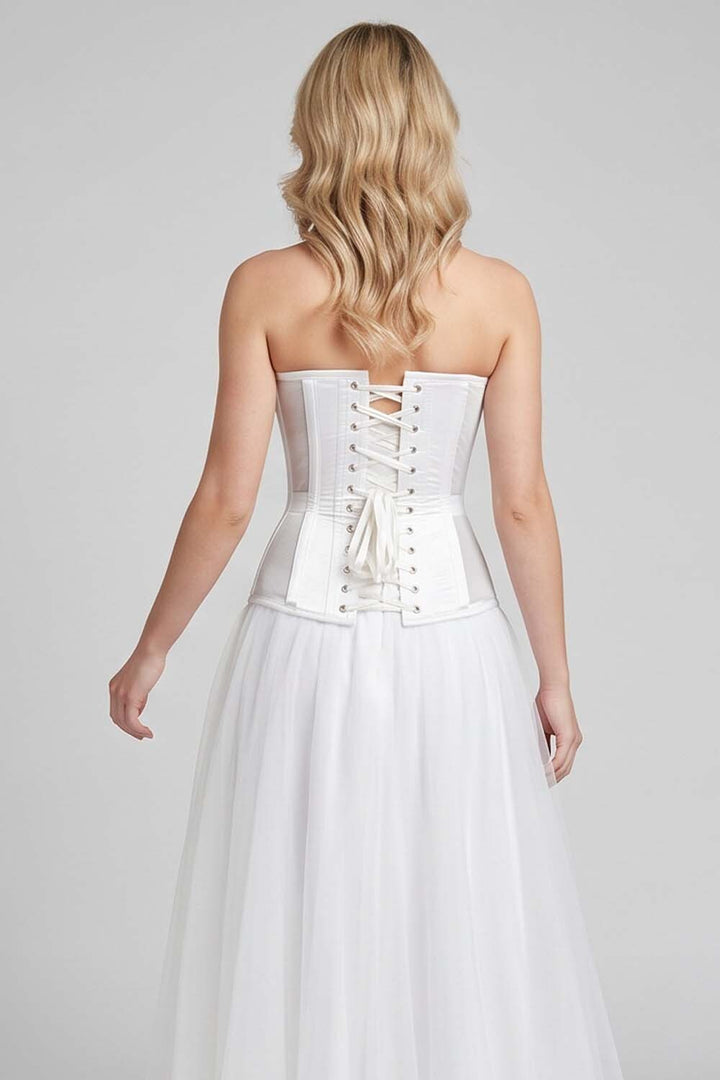 A woman shown from the back wearing a LUXE NOIR CORSET strapless white corset-style dress with a structured waist and a flowing tulle skirt, against a light gray studio background.